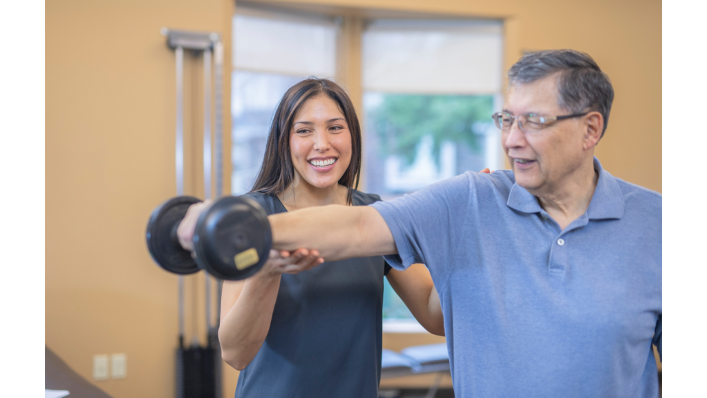 A female occupational therapist assists a male patient lifting a dumbbell