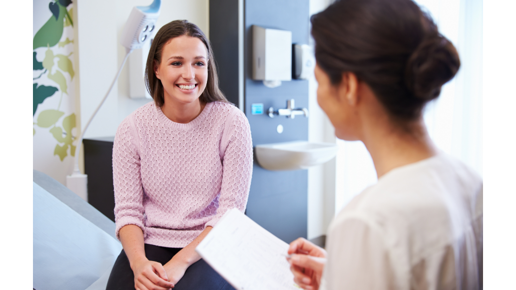 A female patient smiles at the clinician attending her