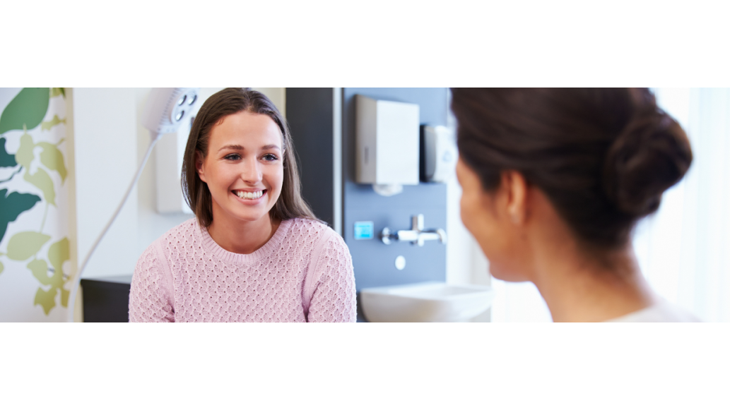 A female patient smiles at the clinician attending her