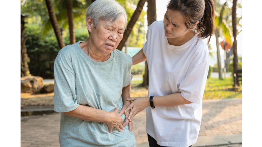 elderly woman holding abdomen in pain