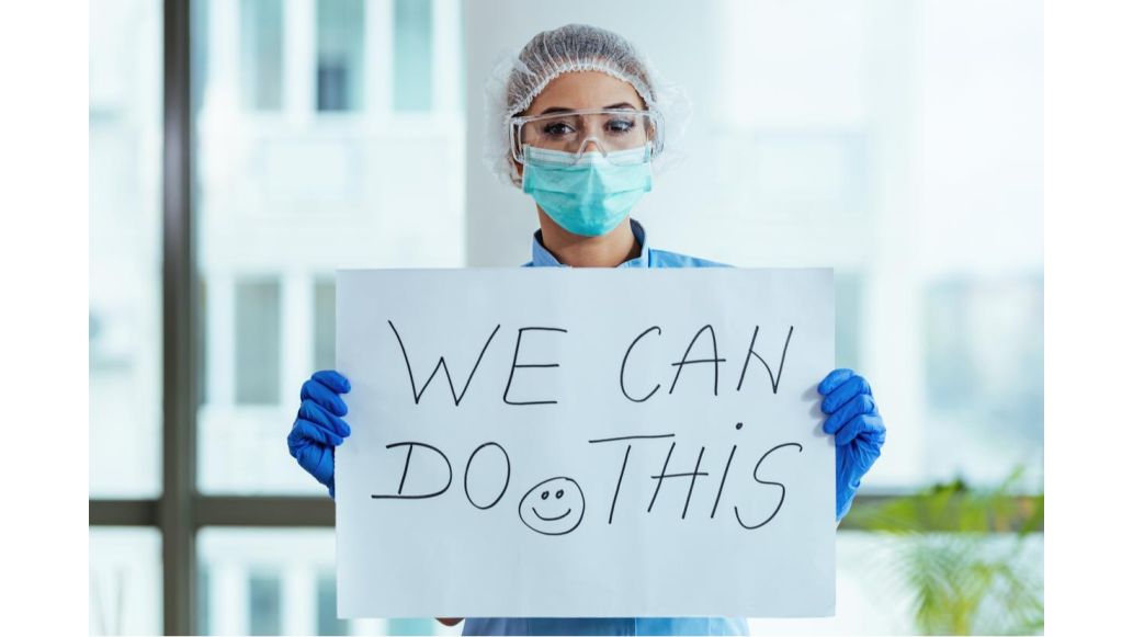 health care worker holding positive sign