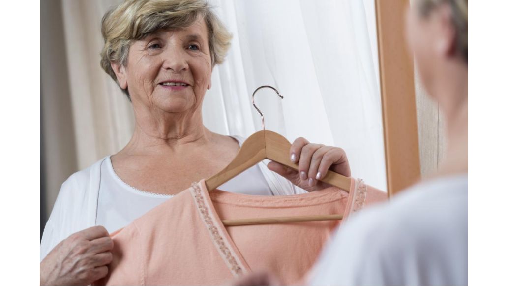 older woman holding up shirt on hanger