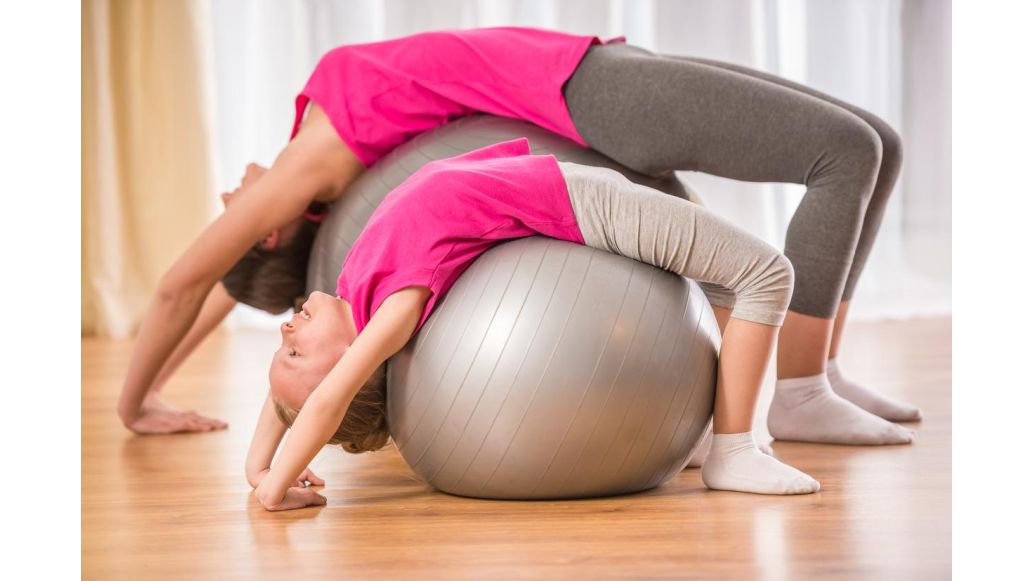 mom and daughter stretching on ball