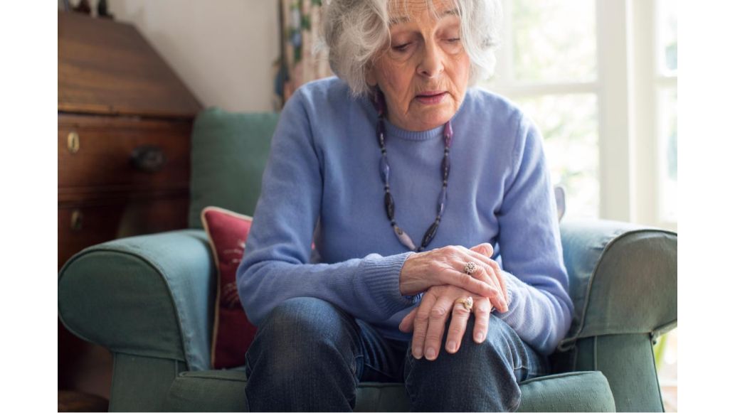 elder woman in chair holding wrist