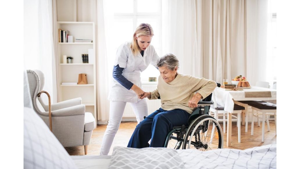 Nurse helping someone out of a wheelchair 
