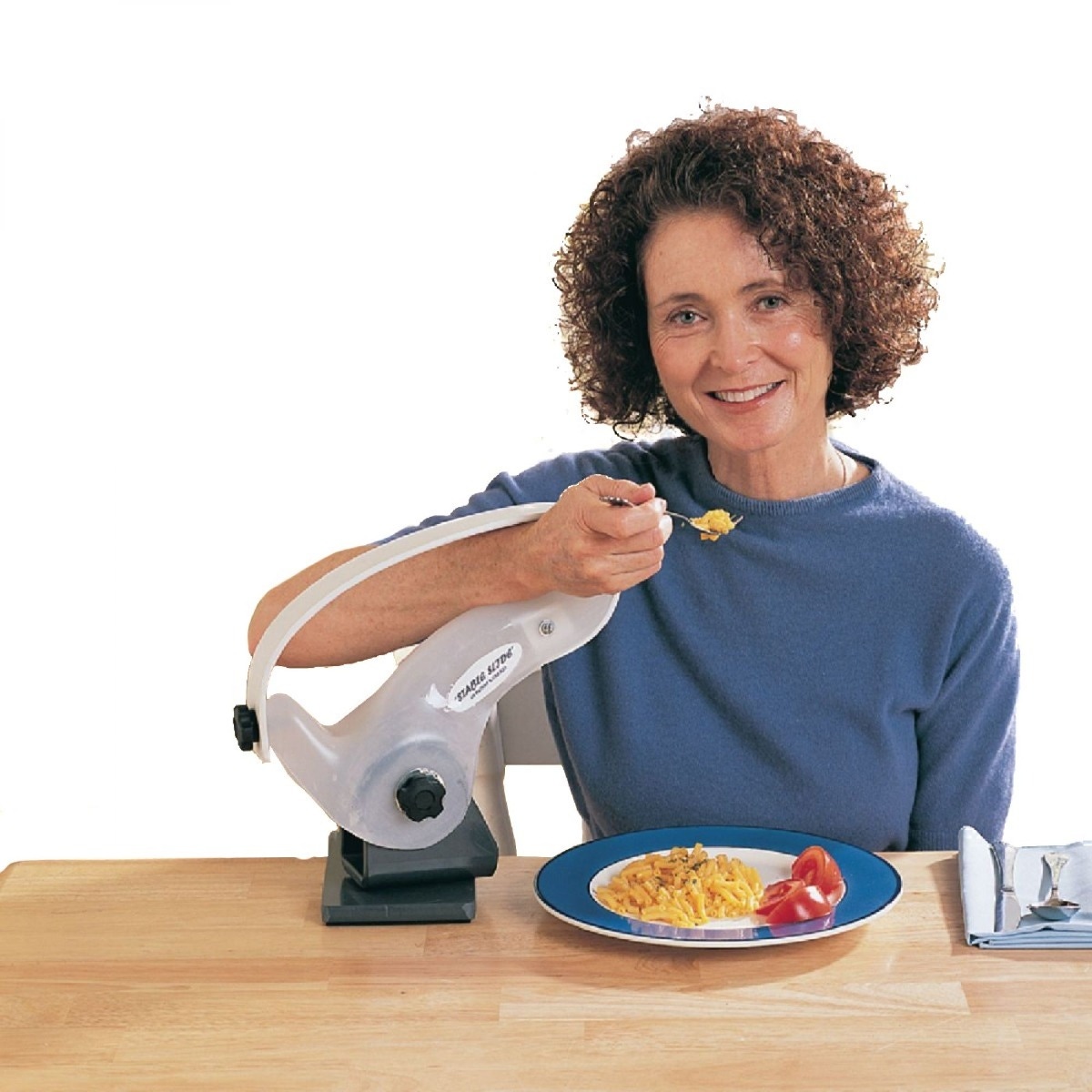 Woman smiling while using the Stable Slide Self-Feeding Support dining aid to support her arm while eating