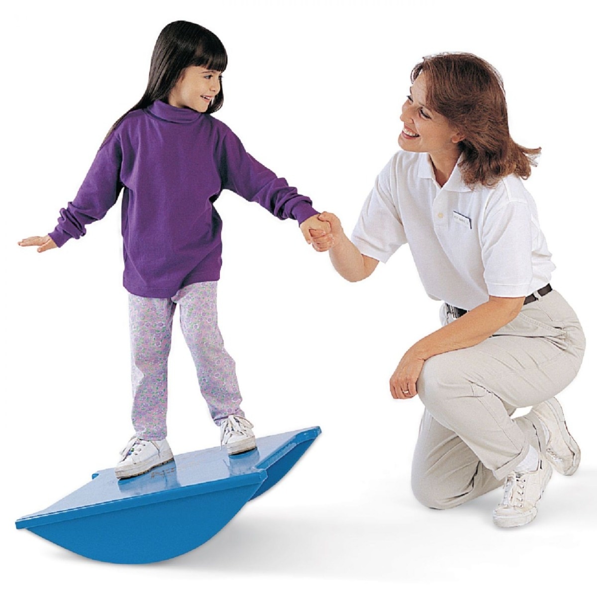 Physiotherapist holding onto happy child's hand to support the child while they balance on a blue rocker board