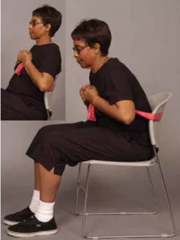 woman in wheelchair using red resistance band to complete seated chest exercise