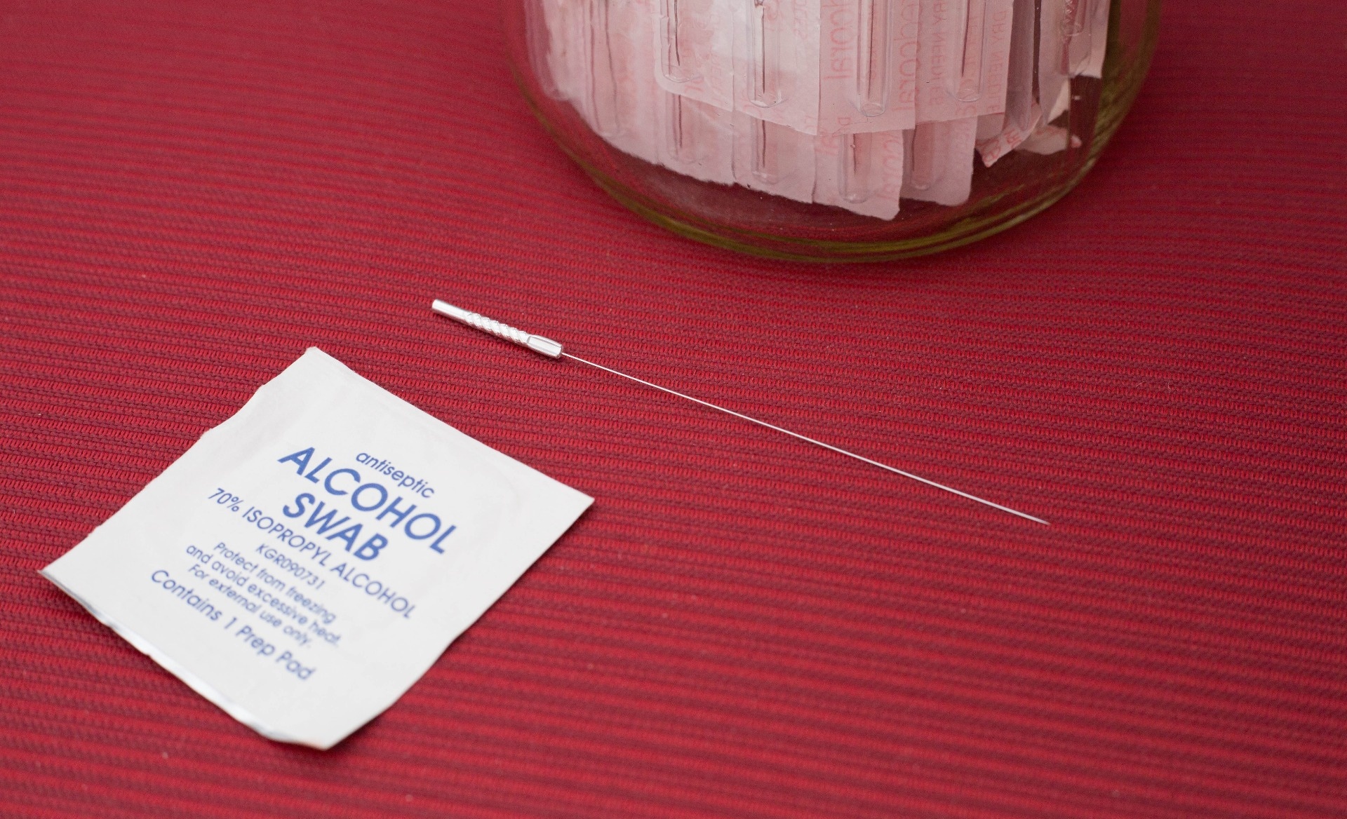 Photo of an alcohol swap packet next to a dry needling needle