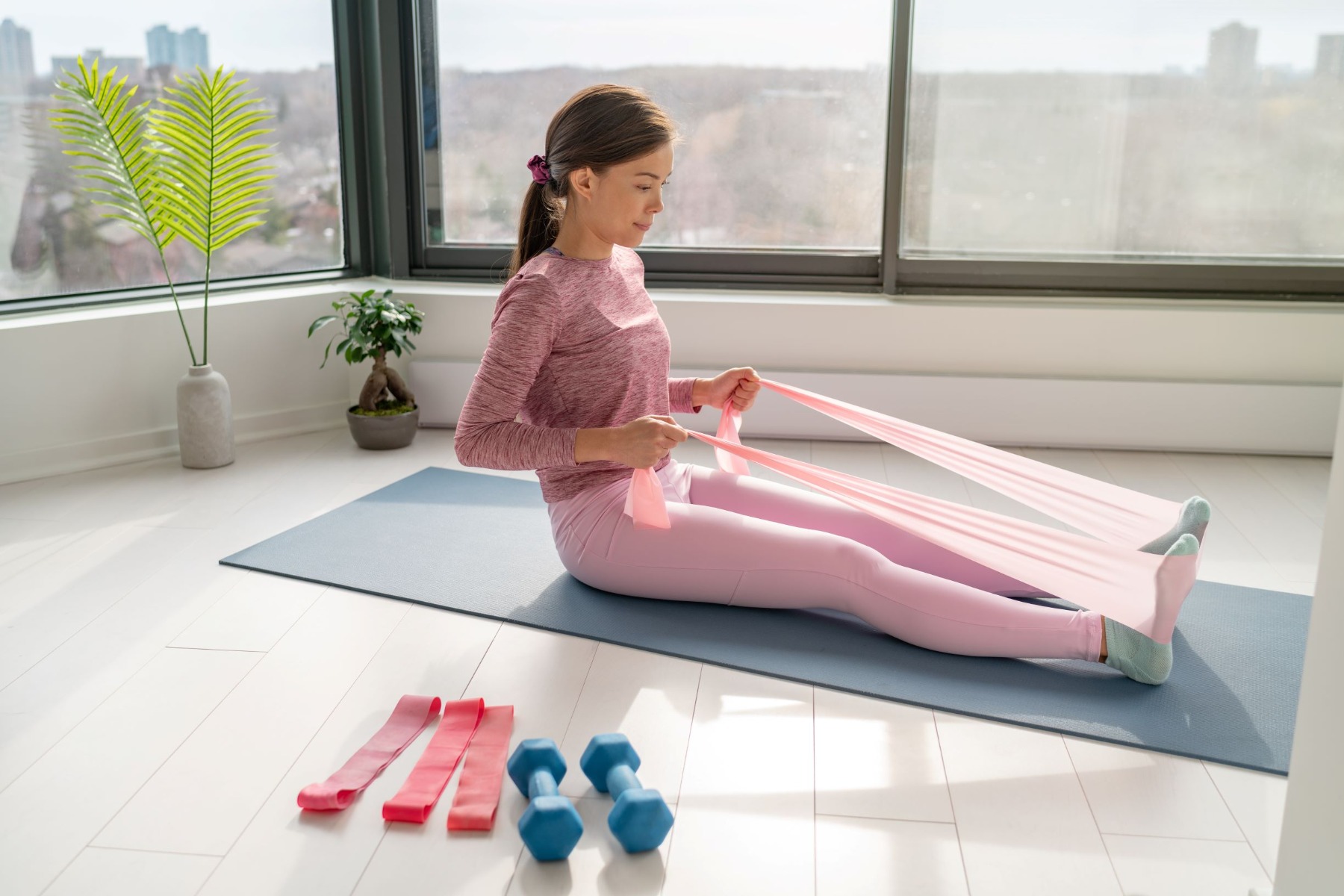 Woman sitting on mat doing row exercise with resistance band