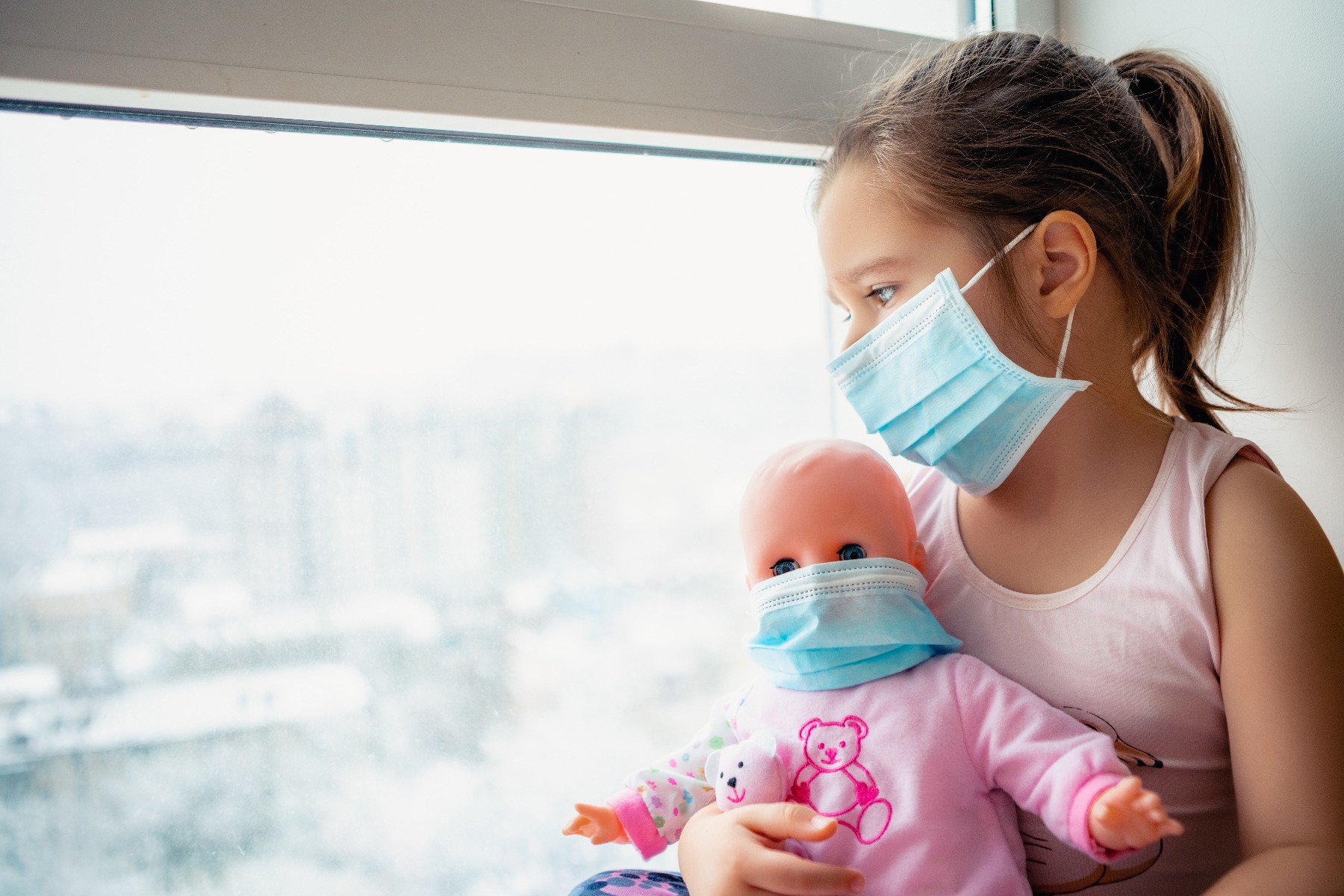 child with mask holding doll wearing mask