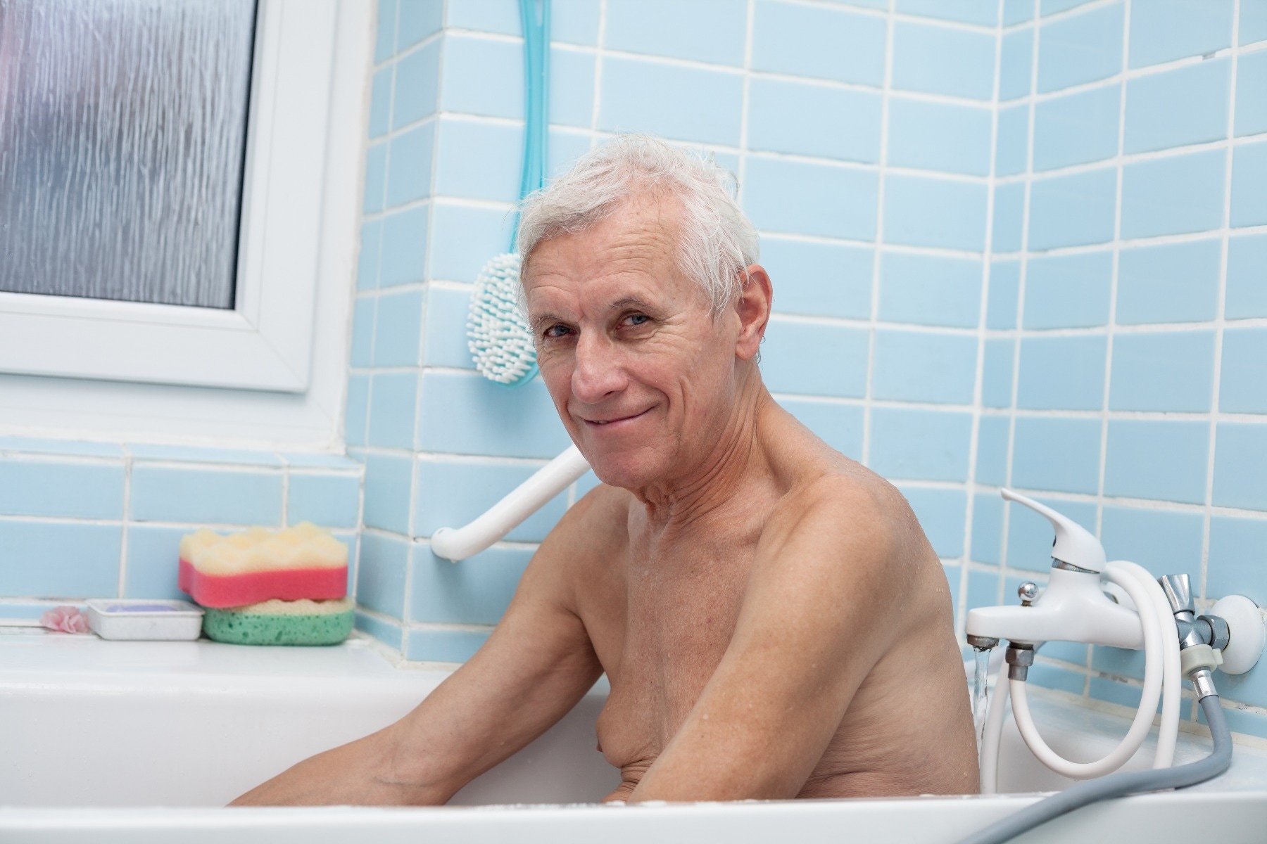 Elderly man seated in bathtub