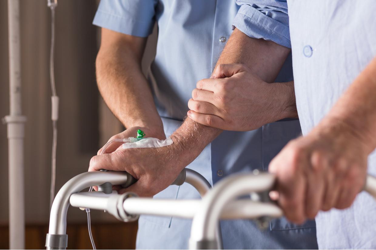 hospital worker helping patient walk