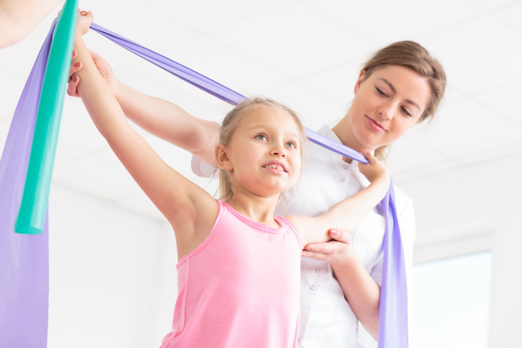 woman helping girl stretch with stretch bands