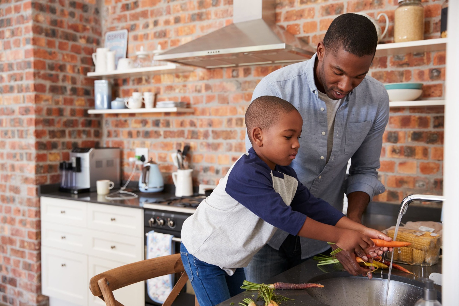 Young boy in the kitchen learning how to cook from his father