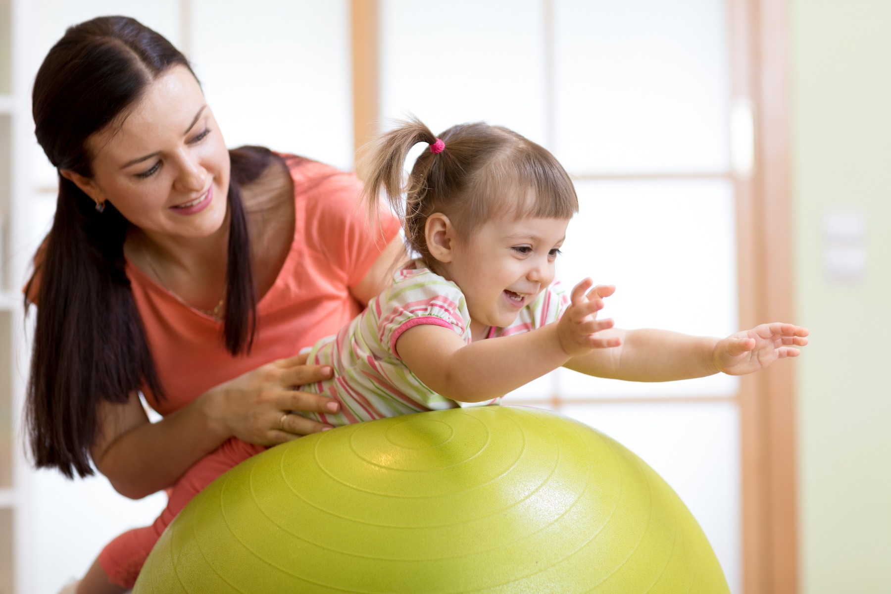 mother helping child on exercise ball