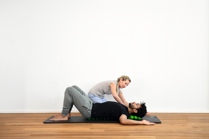 A therapist helps a patient with breathwork as he lays on a SPINEFITTER
